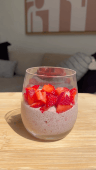Clear cup with strawberry layer and cut up strawberries. 
